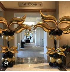 an entrance way with gold and black balloons in the shape of fish, flowers and leaves