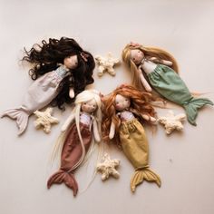 three dolls laying on top of each other next to starfish and seashells