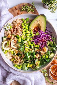 a white bowl filled with vegetables and an avocado