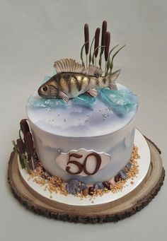 a cake decorated with fish and seaweed on top of a wooden slice that reads 50