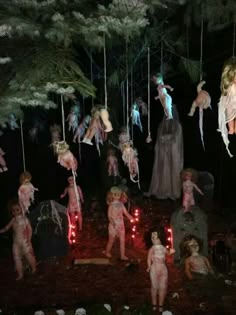 several people dressed up as zombies hanging from strings in the woods at night with lights on them