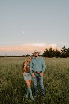 a man and woman are standing in the tall grass with their arms around each other