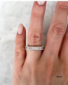 a woman's hand with a diamond ring on her left hand and the middle finger