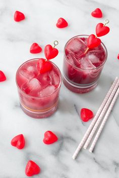 two glasses filled with red liquid next to chopsticks on a white marble surface