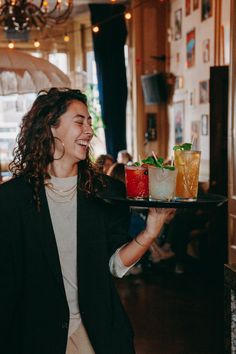 a woman holding a tray with drinks on it