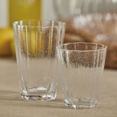 two clear glasses sitting on top of a table next to bananas and other items in the background