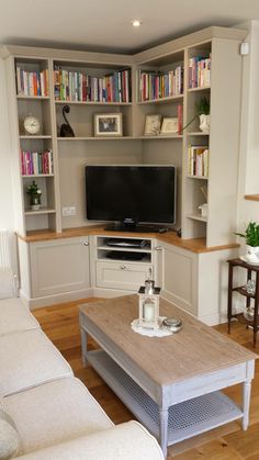 a living room filled with furniture and a flat screen tv on top of a wooden table