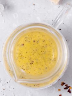 a glass cup filled with yellow liquid on top of a white surface next to pieces of bread