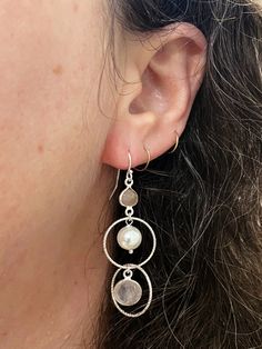 Indulge in the soft, romantic beauty of the Embrace Collection. Handcrafted to perfection, these dangle earrings are a charming addition to any wardrobe. Textured silver ringlets encircle rose quartz and freshwater pearl beads. Complete the set with matching bracelet! Sterling Silver ear wires & details (Lead & Nickel Free) Just over 2" long Each design created is individually crafted in a mountain studio in Floyd, Virginia by Anne Vaughan Original Jewelry Feminine Hypoallergenic Silver Earrings, Silver Feminine Jewelry For Pierced Ears, Silver Dangle Earrings, Feminine Style, Feminine Silver Dangle Earrings, Silver Dangle Earrings Feminine Style, Single Feminine Sterling Silver Earring, Silver Pearl Drop Feminine Jewelry, Feminine Sterling Silver Pearl Drop Jewelry, Feminine Silver Jewelry With Pearl Drop