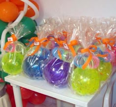 plastic bags filled with different colored balls sitting on a table next to balloons and streamers