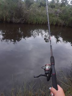 a person holding a fishing rod next to a body of water