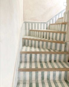 a set of stairs with green and white striped carpet on the bottom, next to a wall