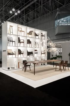 a room with several chairs and tables on display in front of a large white wall