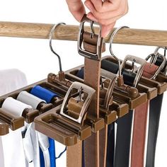 a person is holding onto a rack with several different colored belts hanging from it's sides