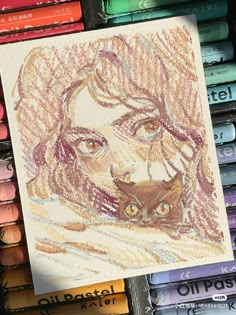 colored crayons are next to a drawing of a woman's face and cat