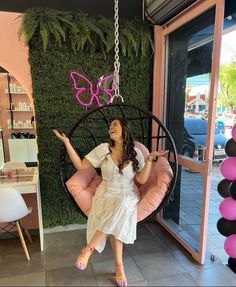 a woman sitting in a swing chair with a pink butterfly on it's back