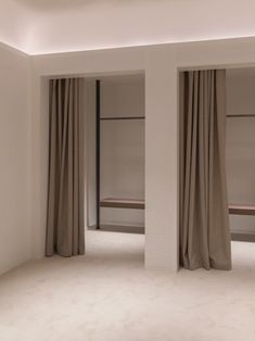 an empty room with two large windows and drapes on the side of each window