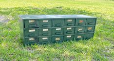 a green filing cabinet sitting on top of a lush green field