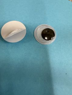 an egg is sitting on a blue surface next to a white cup with black liquid in it