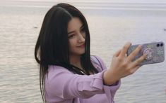 a woman taking a selfie with her cell phone in front of some water and birds