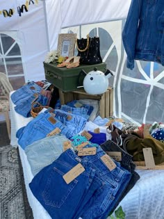 an assortment of jeans and other items on a table in front of a white tent