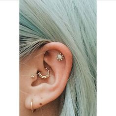 a person with green hair wearing ear piercings