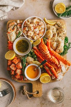 seafood platter with lobster, crab legs, shrimp and lemon wedges on wooden cutting board