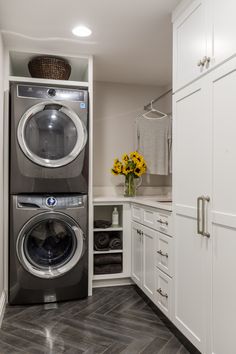 a washer and dryer are in the corner of this laundry room with white cabinets