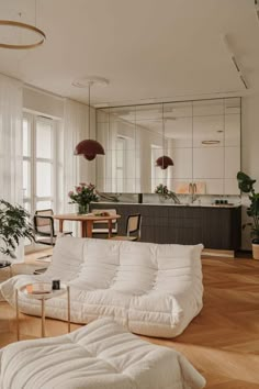 a living room filled with furniture next to a kitchen and dining room table on top of a hard wood floor