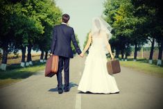 the bride and groom are walking down the road holding suitcases in their hands as if they were just married