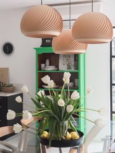 a vase with white flowers sitting on top of a table next to a book shelf