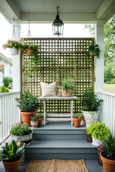 A beautiful farmhouse porch featuring a lattice privacy screen, decorated with potted plants and inviting vintage decor, perfect for summer entertaining and outdoor relaxation. Bungalow Porch Ideas, Vintage Metal Glider, Bungalow Porch, Lattice Screen, Rustic Birdhouse, Summer Lounge, Charming Farmhouse