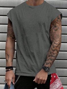 a man with tattoos is holding his hand in his pocket and looking at the camera