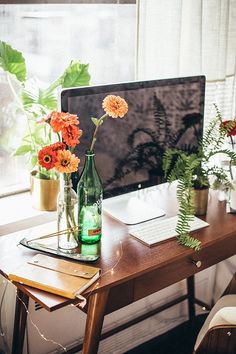 a computer desk with flowers in vases on it