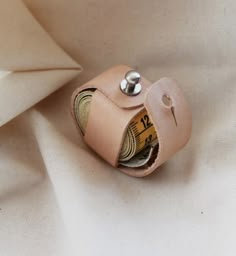 a leather cuff with a measuring tape sticking out of it's center, sitting on a white fabric