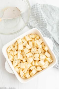 a white bowl filled with tofu next to a spoon