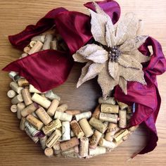 a wreath made out of wine corks with a red ribbon around it and a poinsettia