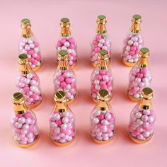 there are many pink and white candies in the bottles with gold caps on them