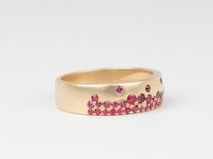 a gold ring with pink and red stones on the inside, set against a white background