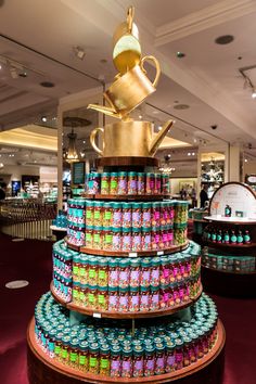 a large stack of cans stacked on top of each other next to a gold tea pot