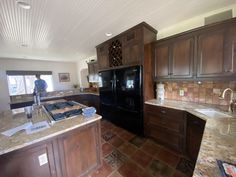 a large kitchen with granite counter tops and wooden cabinets, along with a black refrigerator freezer