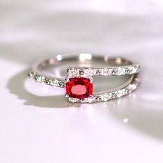 a close up of a ring with a red stone in the middle and white diamonds around it