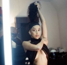 a naked woman is standing in front of a mirror with her arms behind her head