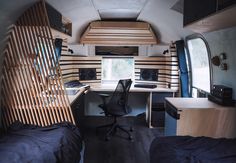 the interior of a camper with two beds, desk and computer on each side