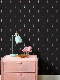 pink and black wallpaper in a room with a lamp on top of a dresser