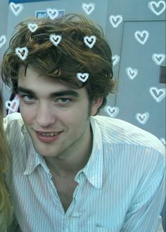 a young man and woman are smiling for the camera with hearts drawn on their hair