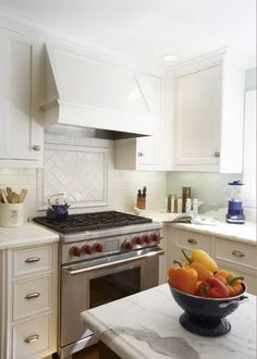 a bowl of fruit is sitting on the counter in this white kitchen with stainless steel appliances