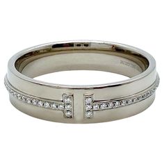 Tiffany & Co. T Collection Diamond Band Ring Style: Band Ref. number: 60150916 Metal: 18kt White Gold Rhodium Plated for Brilliance Size: 9.75 Measurements: 5.5 MM Main Diamond: 76 Round Brilliant Diamond 0.12 tcw Color & Clarity: White & Clean Hallmark: ©TIFFANY&Co. Au750 BELGIUM Includes: T&C Ring Pouch Est. Retail: $4,650.00 Sku#13138TBB04302024 Designer Formal Diamond Ring With Single Cut Diamonds, Contemporary Hallmarked Rings For Formal Occasions, Luxury White Gold Band With Brilliant Cut, Luxury White Gold Bands With Brilliant Cut, Designer Wedding Diamond Ring With Polished Finish, Designer Round Diamond Ring For Formal Occasions, Designer Diamond White Rings For Formal Occasions, Designer Hallmarked Diamond Ring For Formal Occasions, Luxury Bands With Diamond Accents For Formal Events