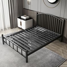 a black metal bed frame sitting on top of a wooden floor next to a window