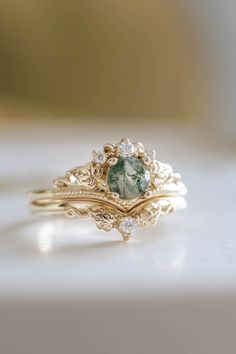 a close up of a ring with a green stone in the middle and two diamonds on each side